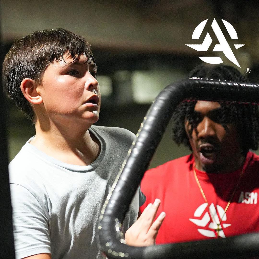 Armed Sports coach guiding a young athlete through a training drill
