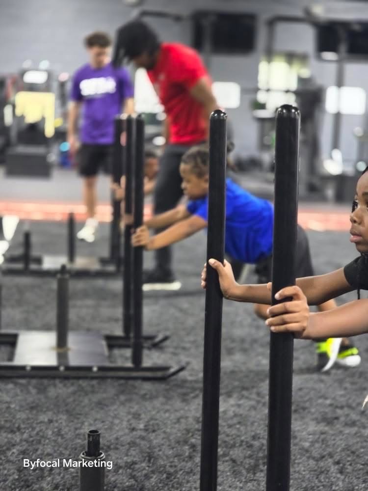 Youth athletes driving weighted sleds during training