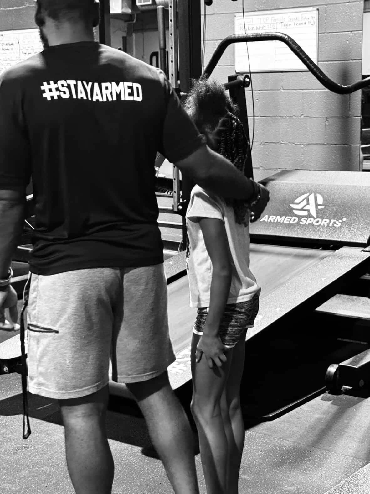 Stay Armed coach working beside a young athlete on the treadmill