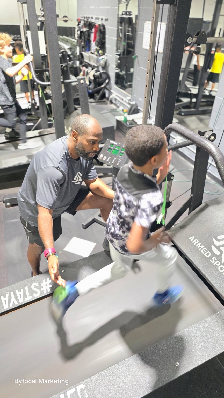 Coach supporting a young athlete during a treadmill speed session