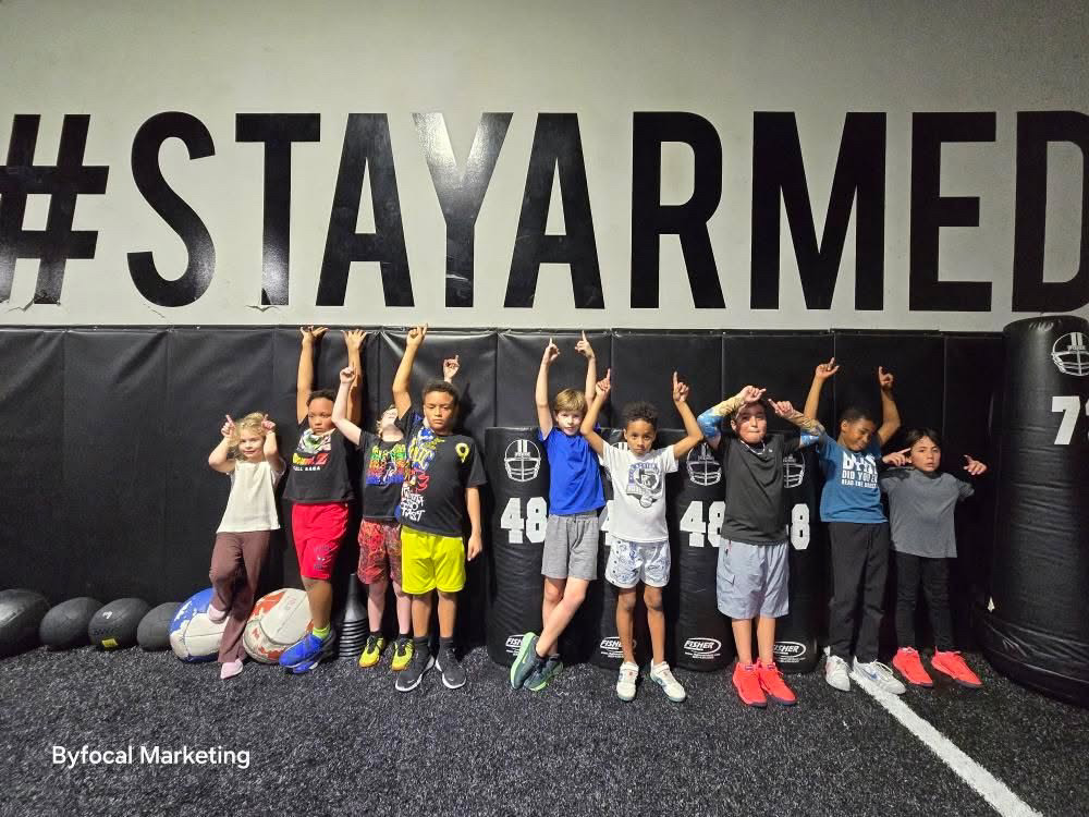 Youth athletes gathered beneath the Stay Armed wall